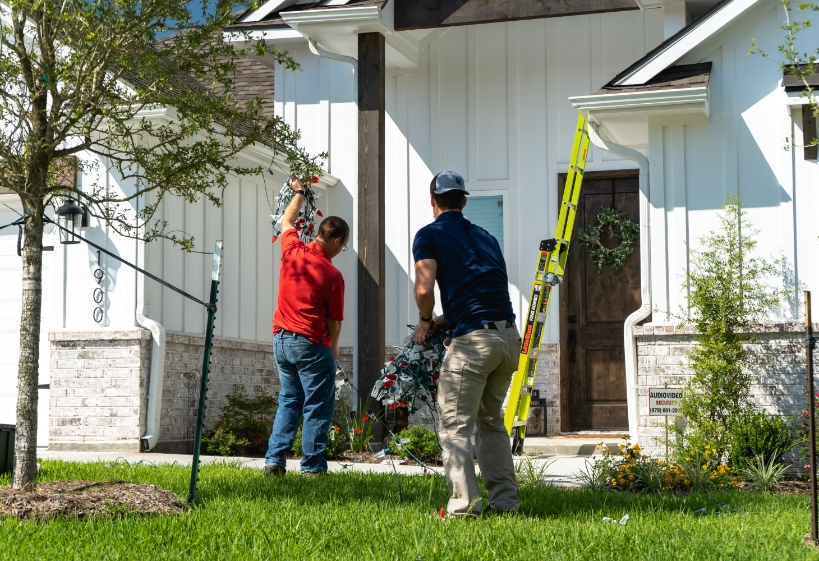 two first responder Christmas light installers getting ready to put lights on a house in South College Station